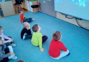 Dzieci siedzą na dywanie i oglądają przedstawienie Elfy trzy